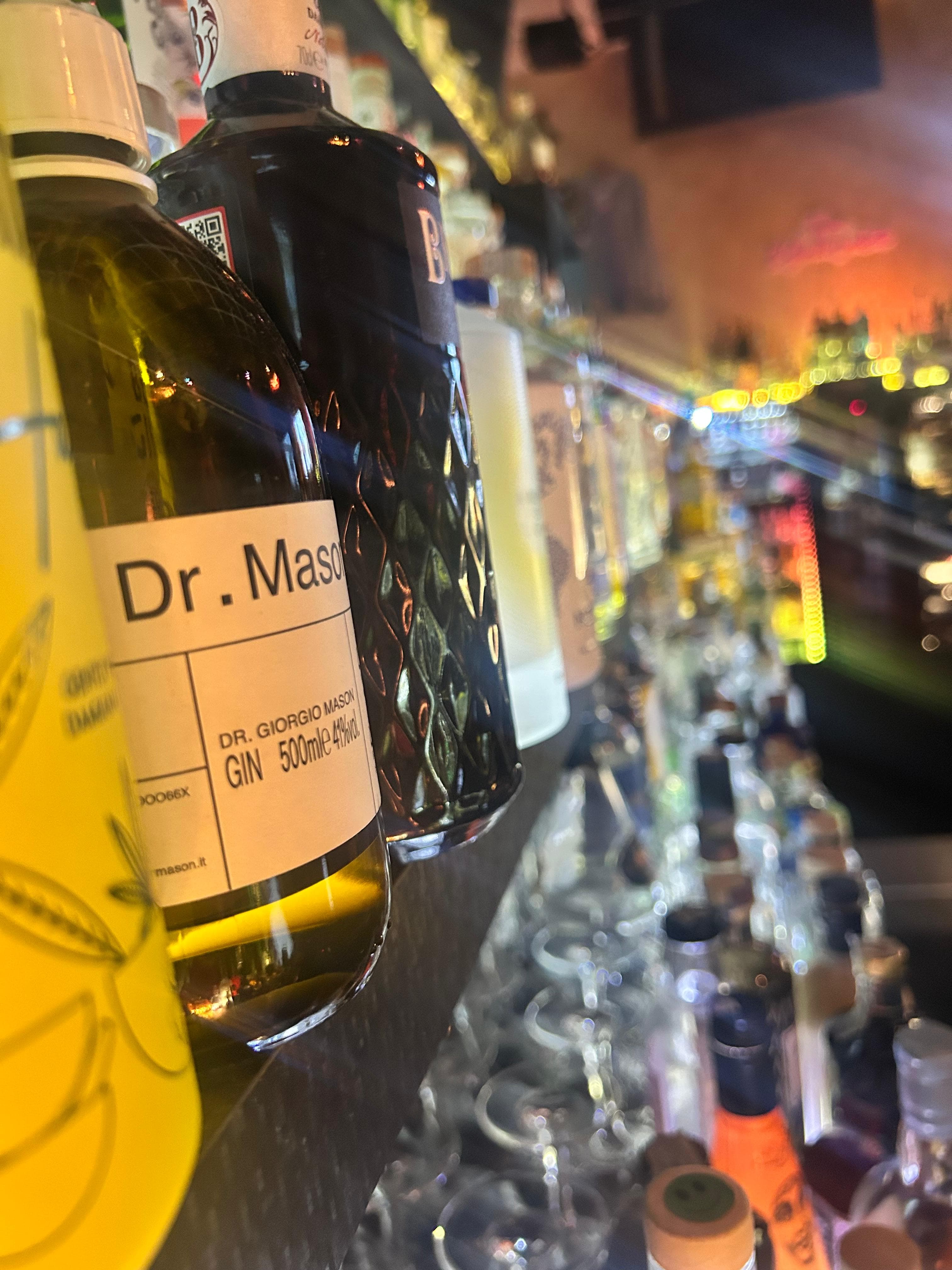 Bottiglie di gin in primo piano, luci della sala sullo sfondo